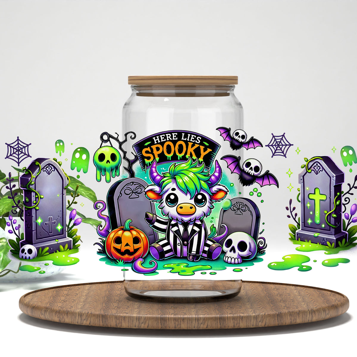 Here Lies Spooky highland cow graveyard UV DTF full wrap on a clear glass can with a bamboo lid