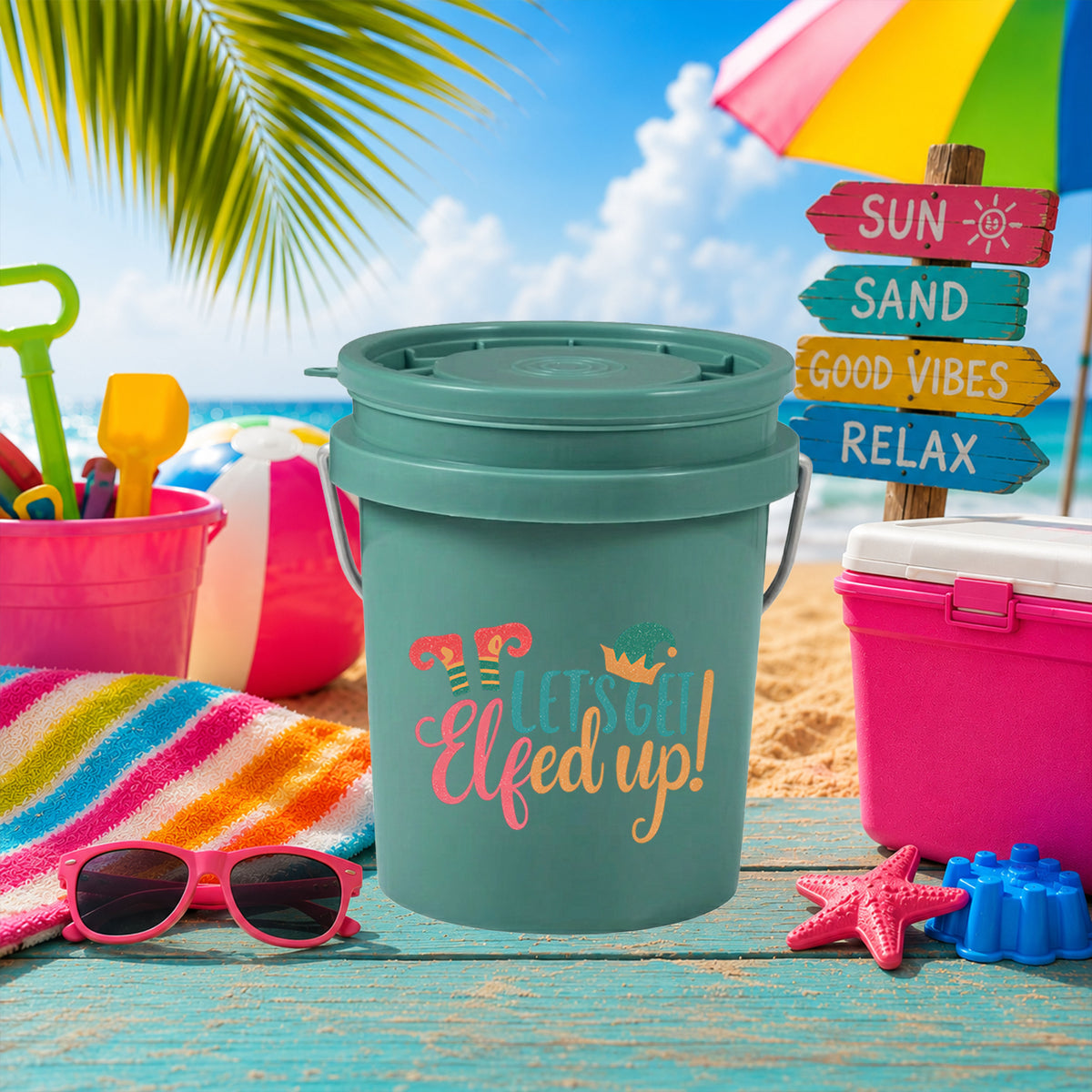 Let's Get Elfed Up UV DTF transfer on a teal mini bucket on the beach
