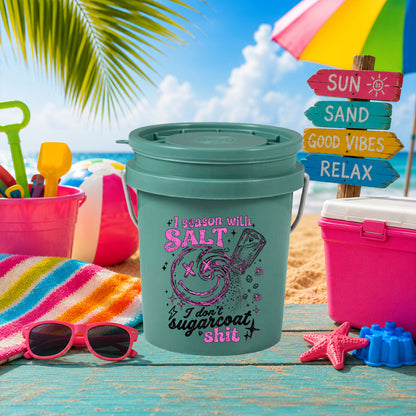 I Season With Salt UV DTF transfer on a teal mini bucket on the beach
