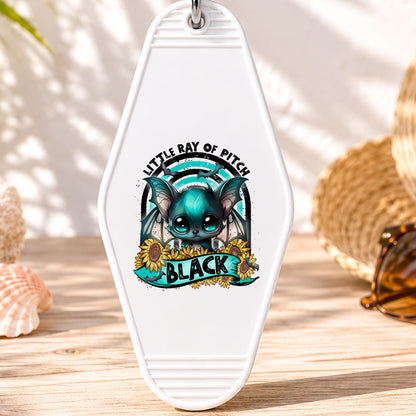 Little Ray of Pitch Black UV DTF transfer on a white motel keychain with beach decor