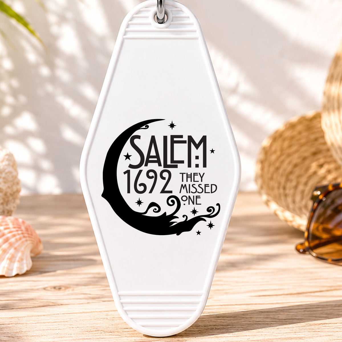 Salem 1692 They Missed One UV DTF transfer on a white motel keychain with beach decor