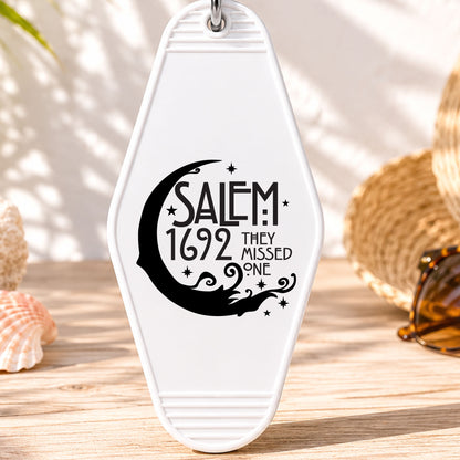 Salem 1692 They Missed One UV DTF transfer on a white motel keychain with beach decor
