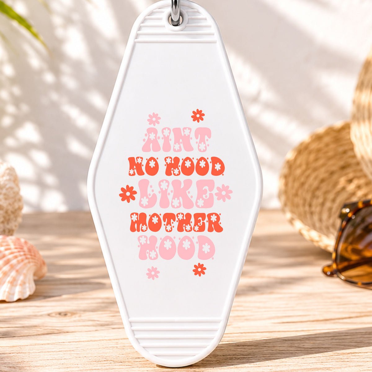 Ain't No Hood Like Motherhood UV DTF transfer on a white motel keychain with beach decor
