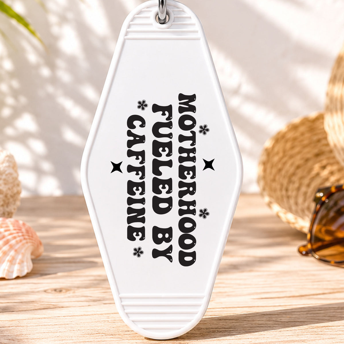 Motherhood Fueled by Caffeine UV DTF transfer on a white motel keychain with beach decor