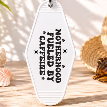 Motherhood Fueled by Caffeine UV DTF transfer on a white motel keychain with beach decor