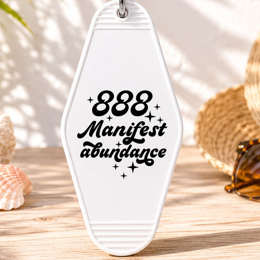 888 Manifest Abundance UV DTF transfer on a white motel keychain with beach decor