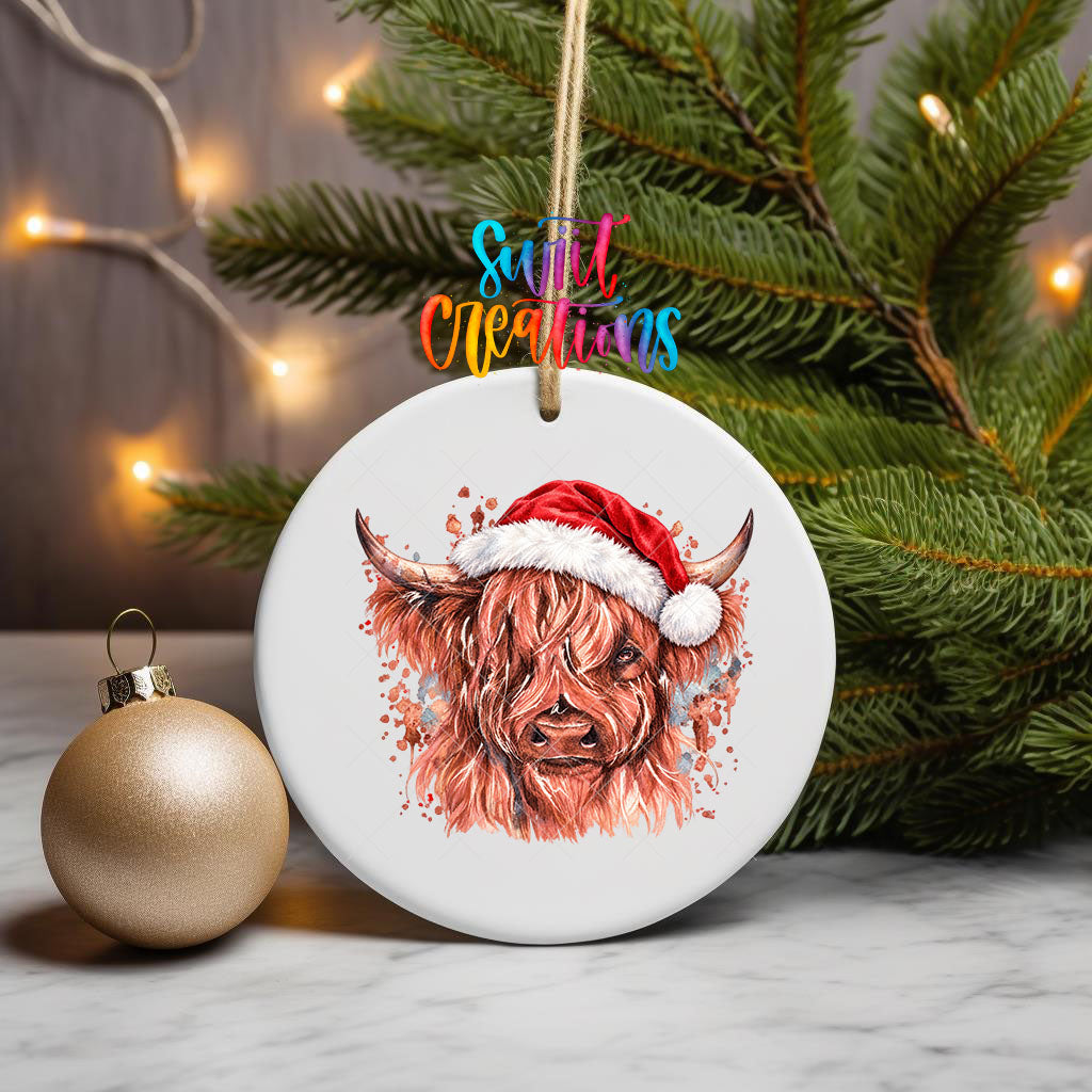 Highland Cow Santa Hat ornament UV DTF transfer on an ornament with pine branches and a gold bauble