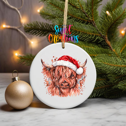 Highland Cow Santa Hat ornament UV DTF transfer on an ornament with pine branches and a gold bauble