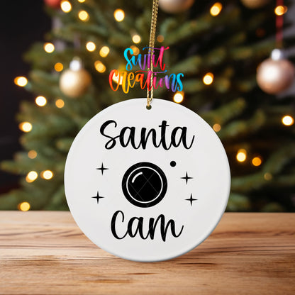 Santa Cam ornament UV DTF transfer on an ornament on a wooden table with tree lights behind it