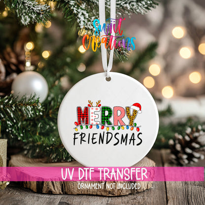 Merry Friendsmas ornament UV DTF transfer on an ornament resting on a wood slice beside a Christmas tree