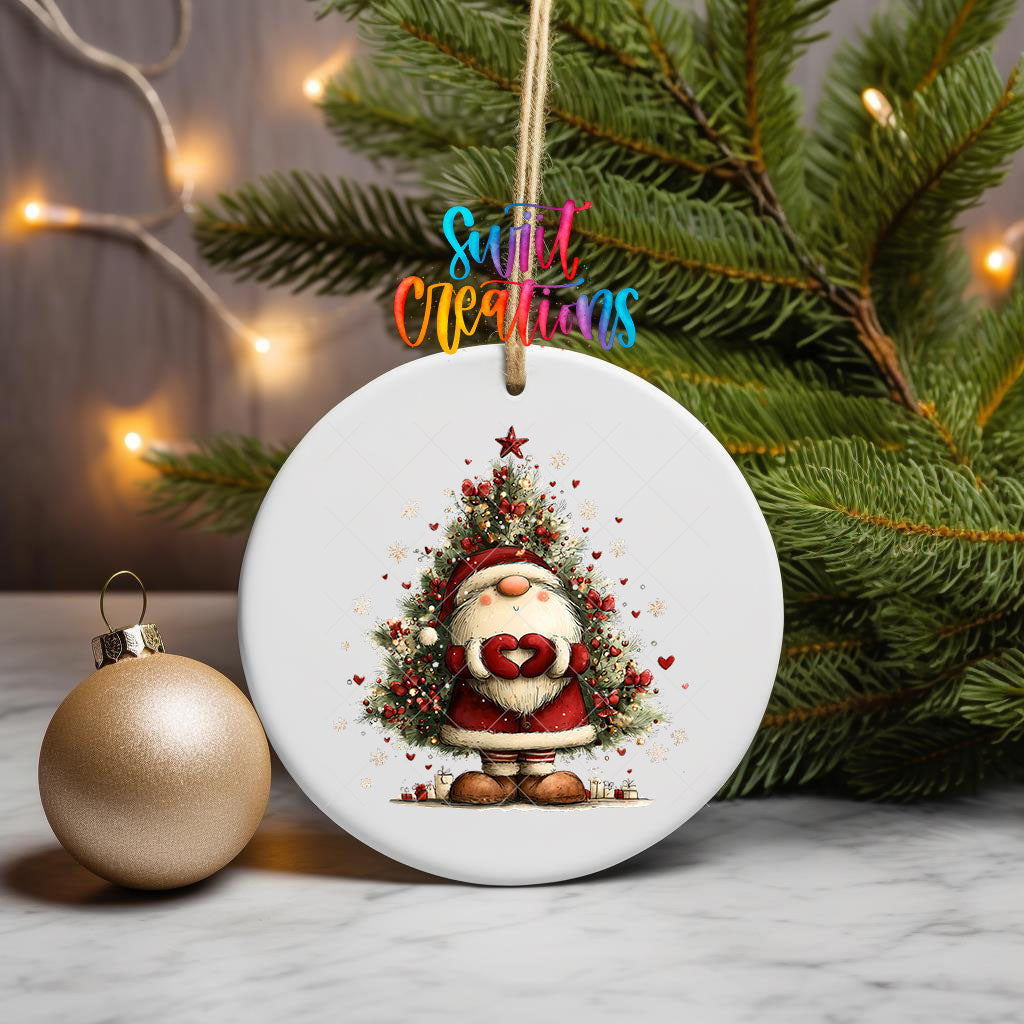 Cute Santa with heart hands in front of a Christmas tree ornament UV DTF transfer on a hanging ornament with pine branches and a gold bauble
