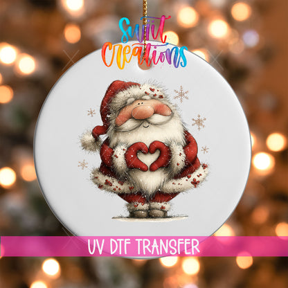 Cute fluffy beard Santa making heart hands UV DTF transfer on a white ornament with a pink UV DTF Transfer banner and bokeh lights