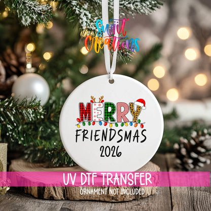 Merry Friendsmas 2026 ornament UV DTF transfer on an ornament resting on a wood slice beside a Christmas tree