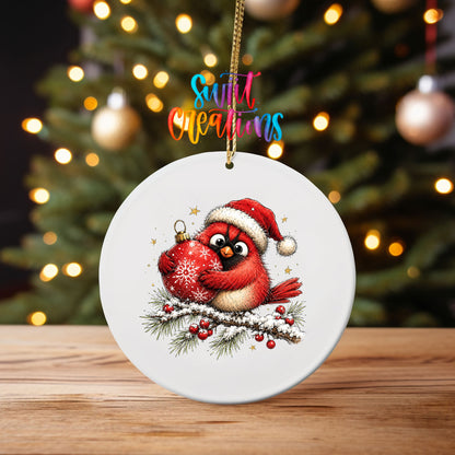 Santa hat cardinal hugging an ornament UV DTF transfer on an ornament on a wooden table with tree lights