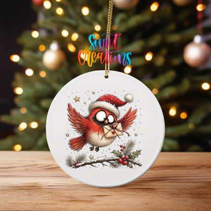 Flying cardinal with a heart envelope UV DTF transfer on an ornament on a wooden table with tree lights