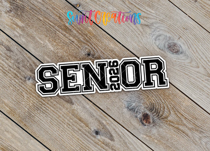 Close-up of the Senior 2026 sticker with 2026 inside the word SENIOR on rustic wood