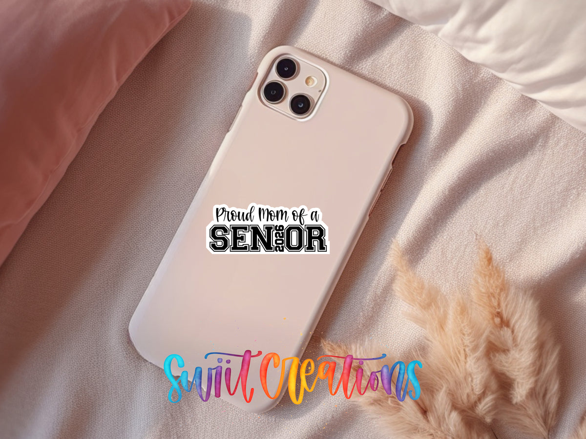 Proud Mom of a 2026 Senior sticker on a pink phone case resting on a bed