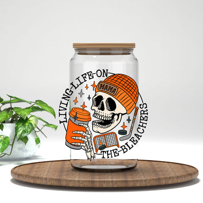 Living Life on the Bleachers skeleton in an orange mama cap UV DTF transfer on a clear glass can