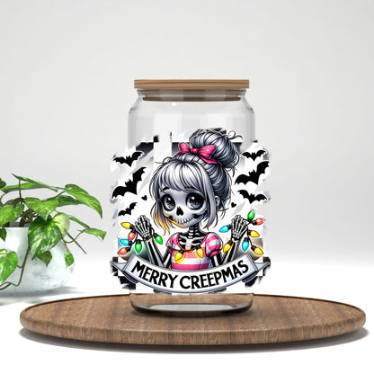 Merry Creepmas skeleton girl UV DTF transfer on a clear glass can on a wood tray with greenery