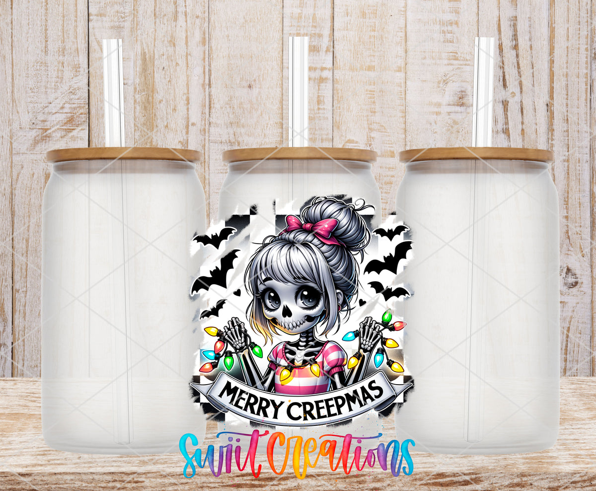 Merry Creepmas skeleton girl UV DTF transfer on three frosted glass cans on a wood background