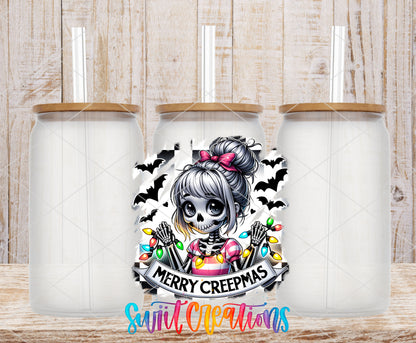 Merry Creepmas skeleton girl UV DTF transfer on three frosted glass cans on a wood background