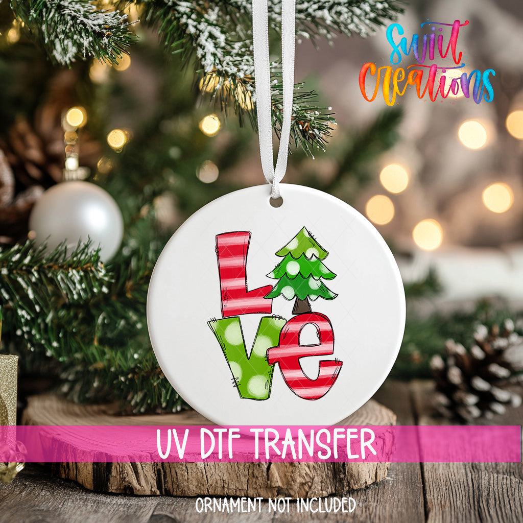 A white Christmas ornament with the word "LOVE" written on it, hanging on a decorated tree.