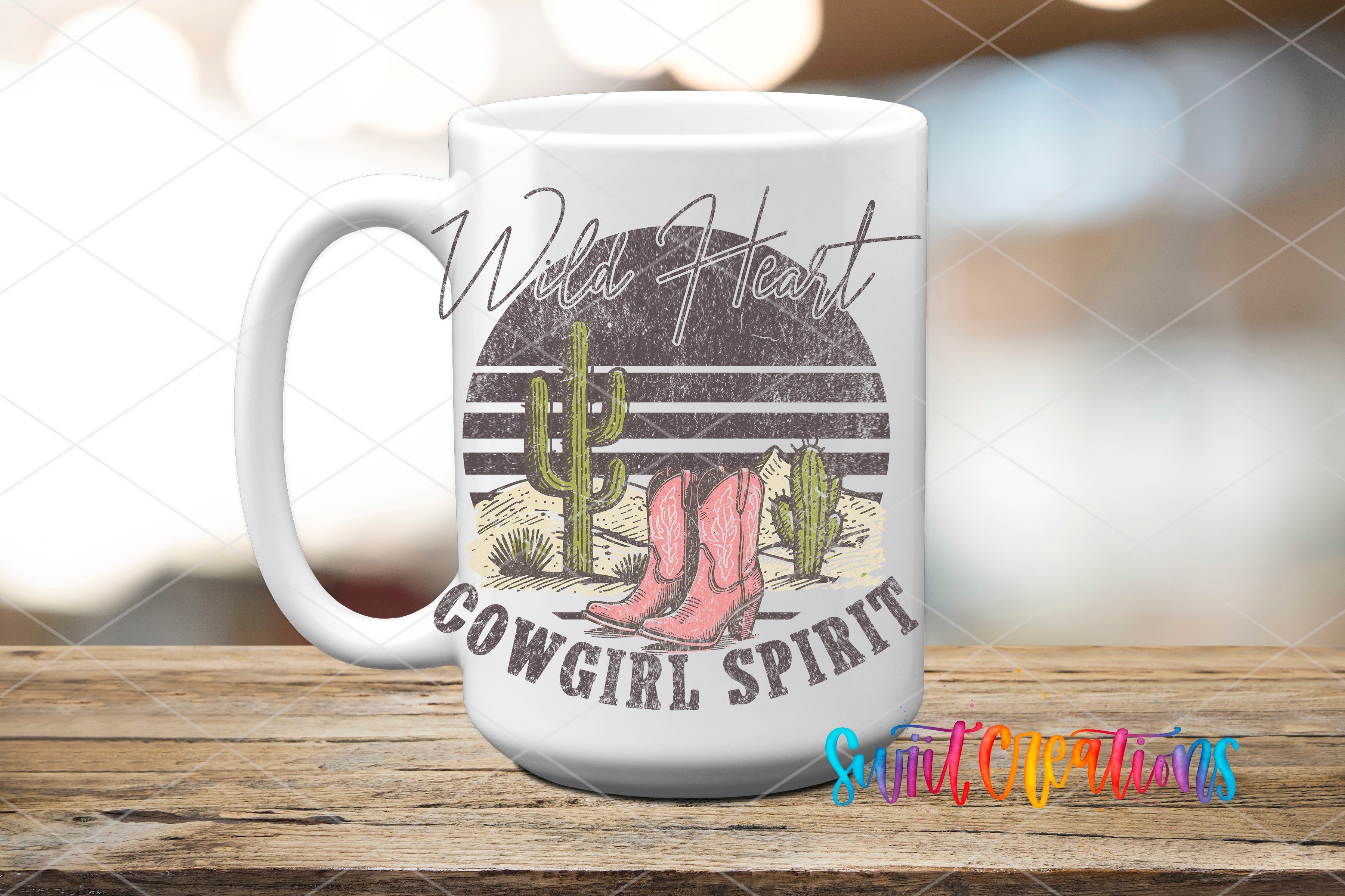 A white ceramic mug with a graphic design featuring a cactus, cowboy boots, and the text "Wild Heart Cowgirl Spirit" printed on it.