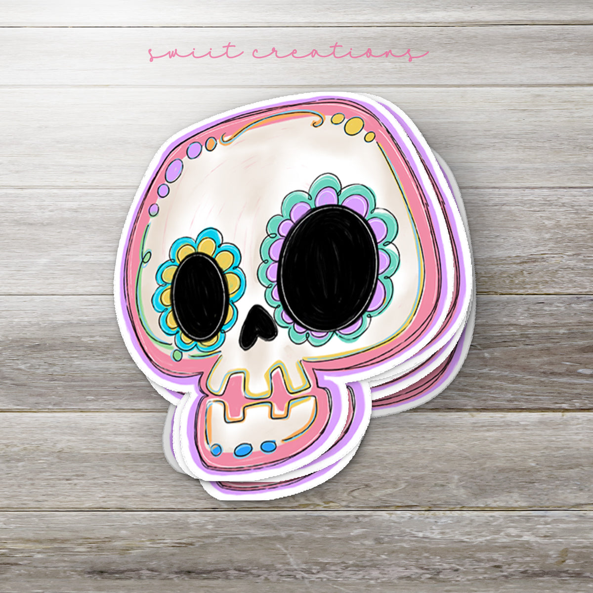 Stack of Pastel Sugar Skull glossy stickers on a gray wood table
