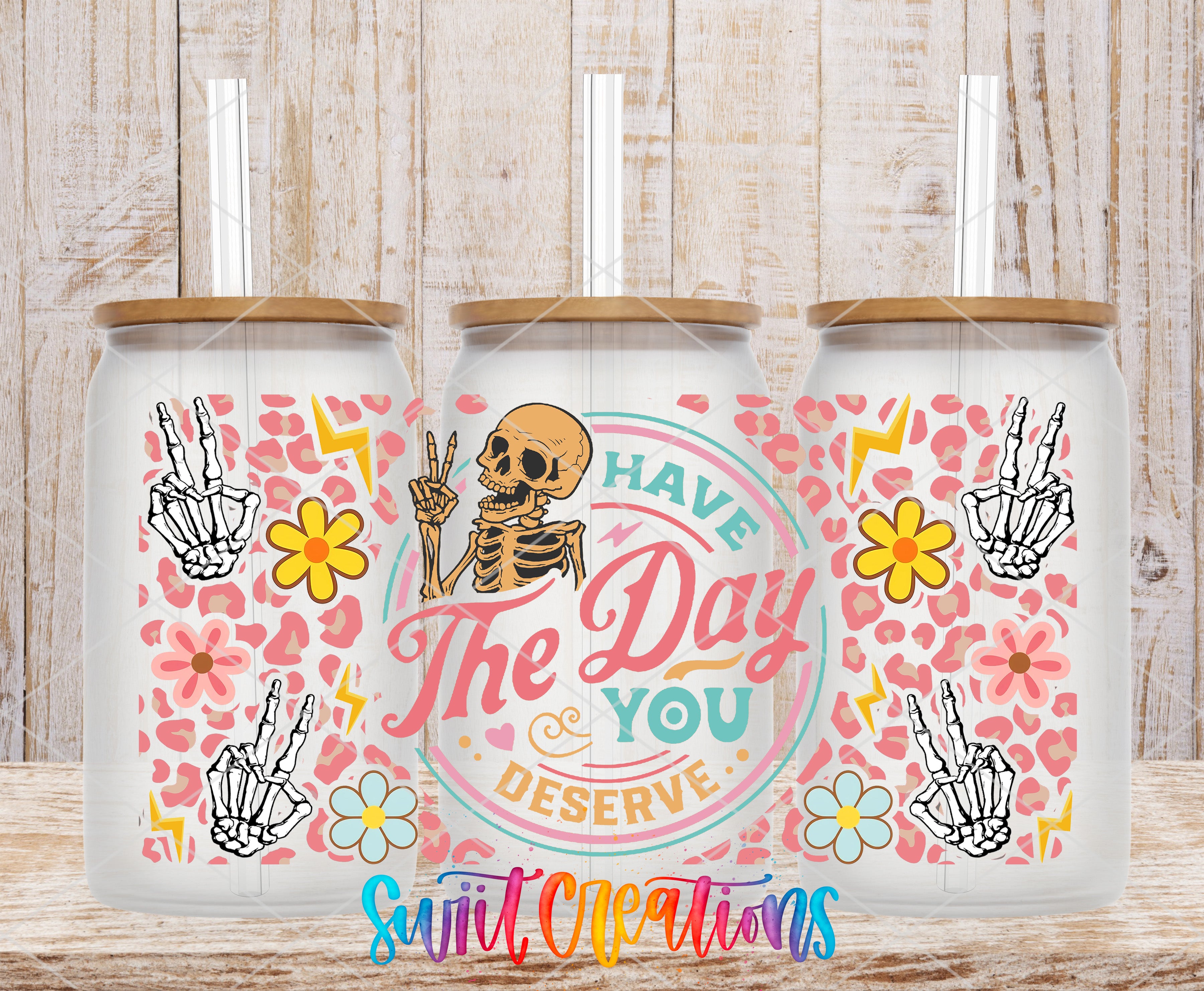 three glass tumblers with a skeleton design and floral patterns. The tumblers have a text that reads "The day you deserve" and are placed on a wooden surface.