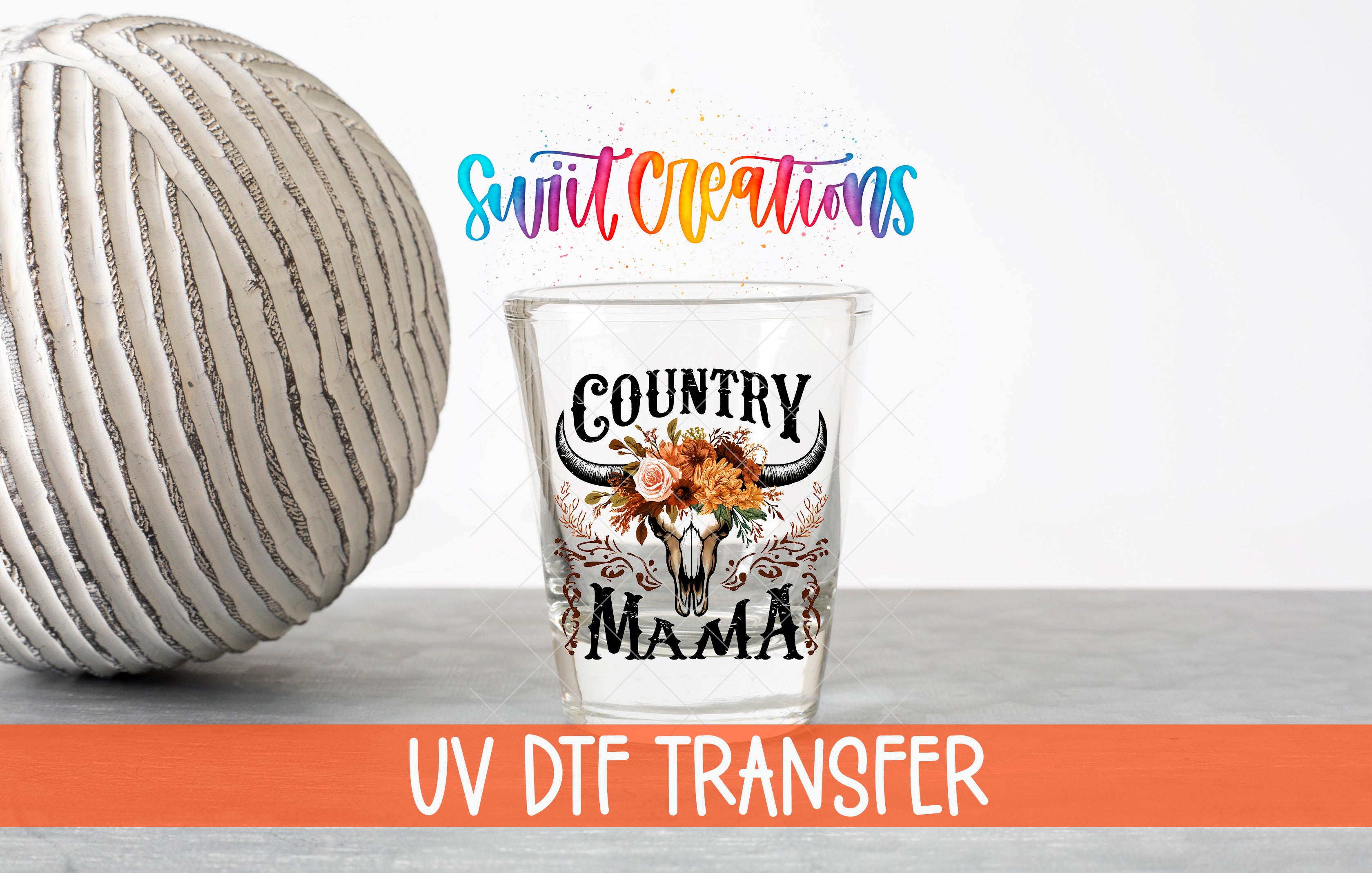 a glass with a decorative design, including a cow skull and floral elements, along with text that says "Country Mama" and "UV DFT Transfer".