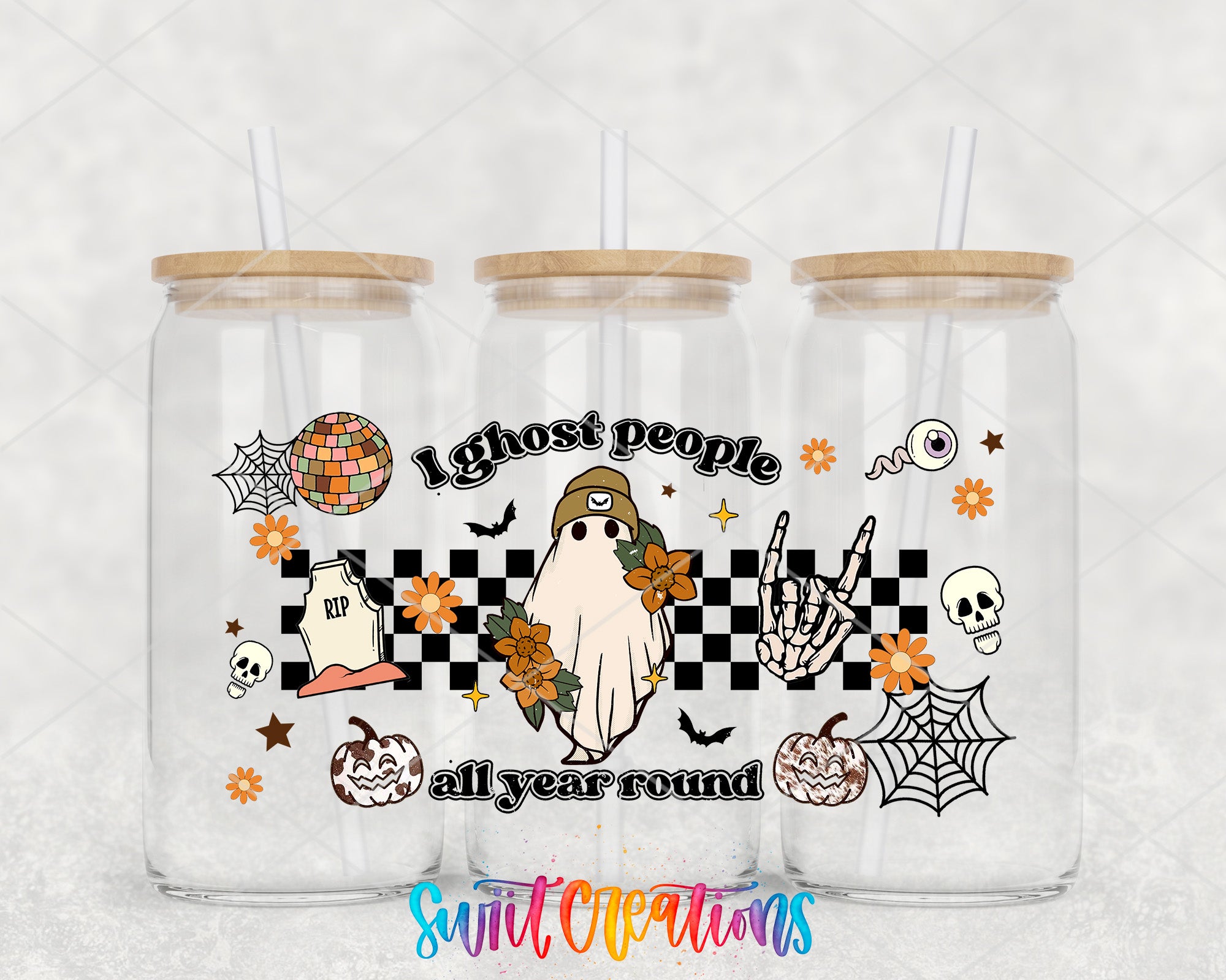 A trio of clear glass tumblers with wooden lids, each adorned with a Halloween-themed design. The design includes a ghost, a skeleton, a skull, a spider, a pumpkin, and a checkerboard pattern. The text "I ghost people all year round" is prominently displayed on the tumblers.