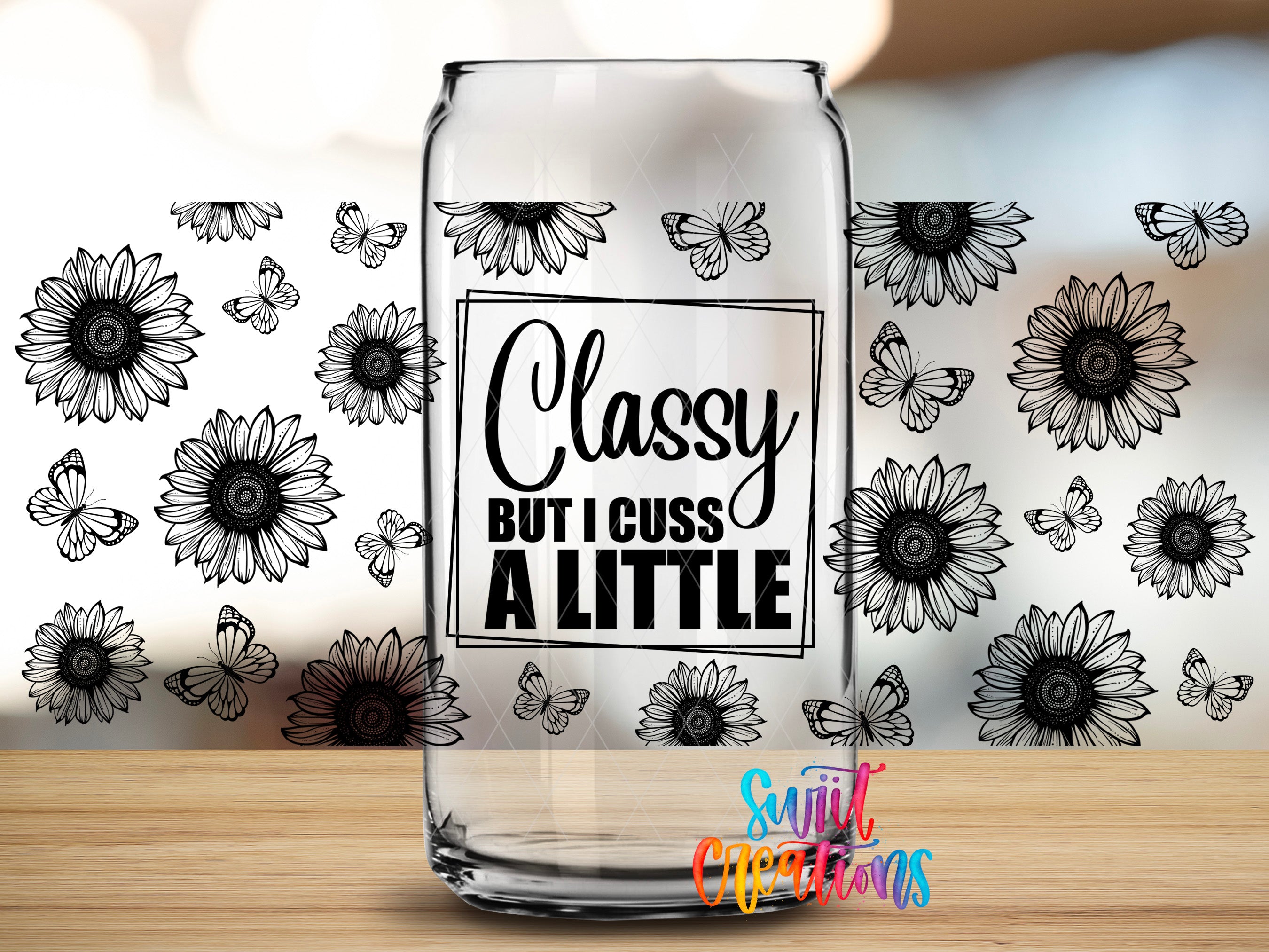 A glass can with a sticker on it, featuring a quote that says "Classy but I cuss a little" surrounded by black and white sunflower designs.