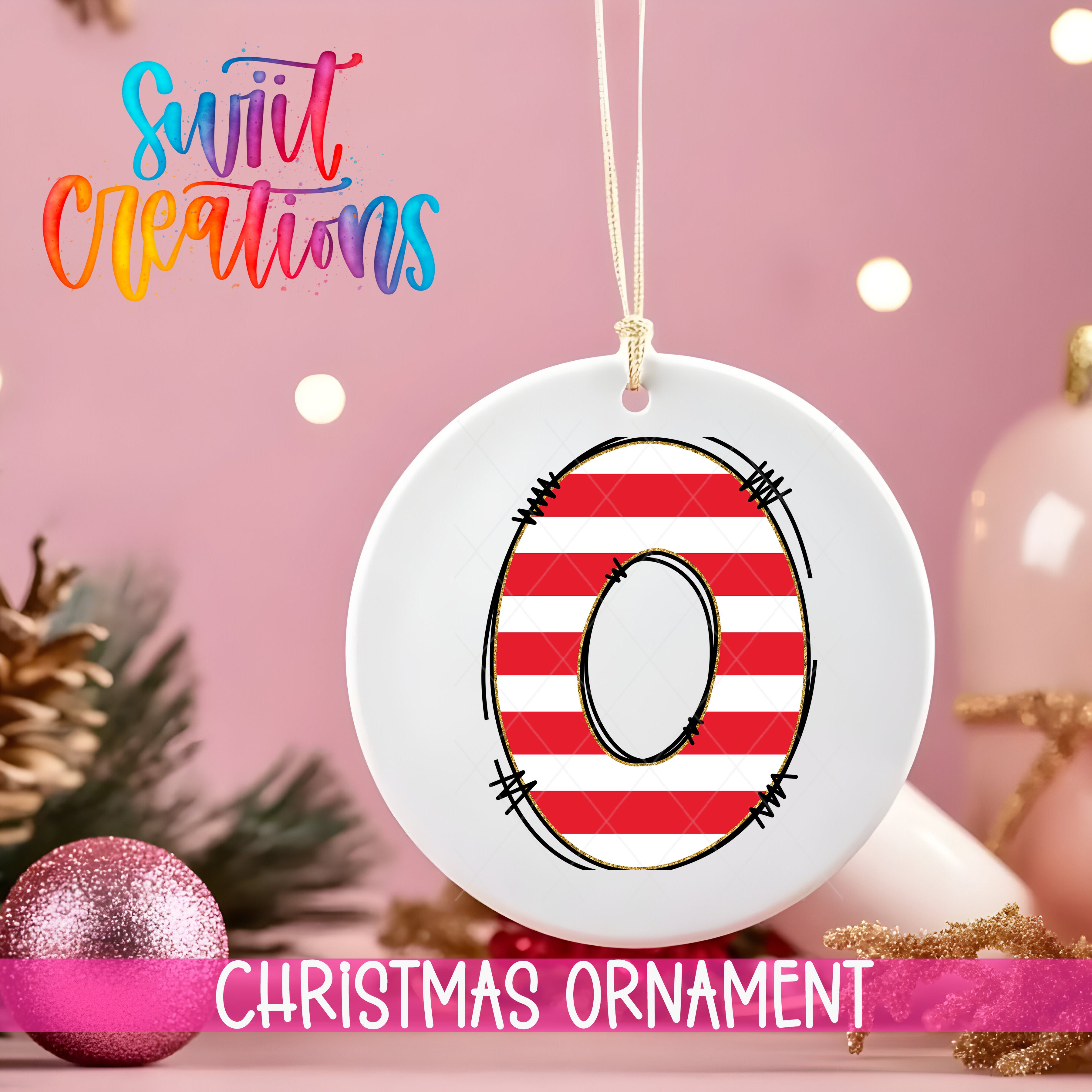 A white Christmas ornament with a red and white striped design, featuring the number 0, is hanging on a string. The ornament is placed on a pink background, with Christmas decorations such as a glittery ornament and pine branches visible in the background.