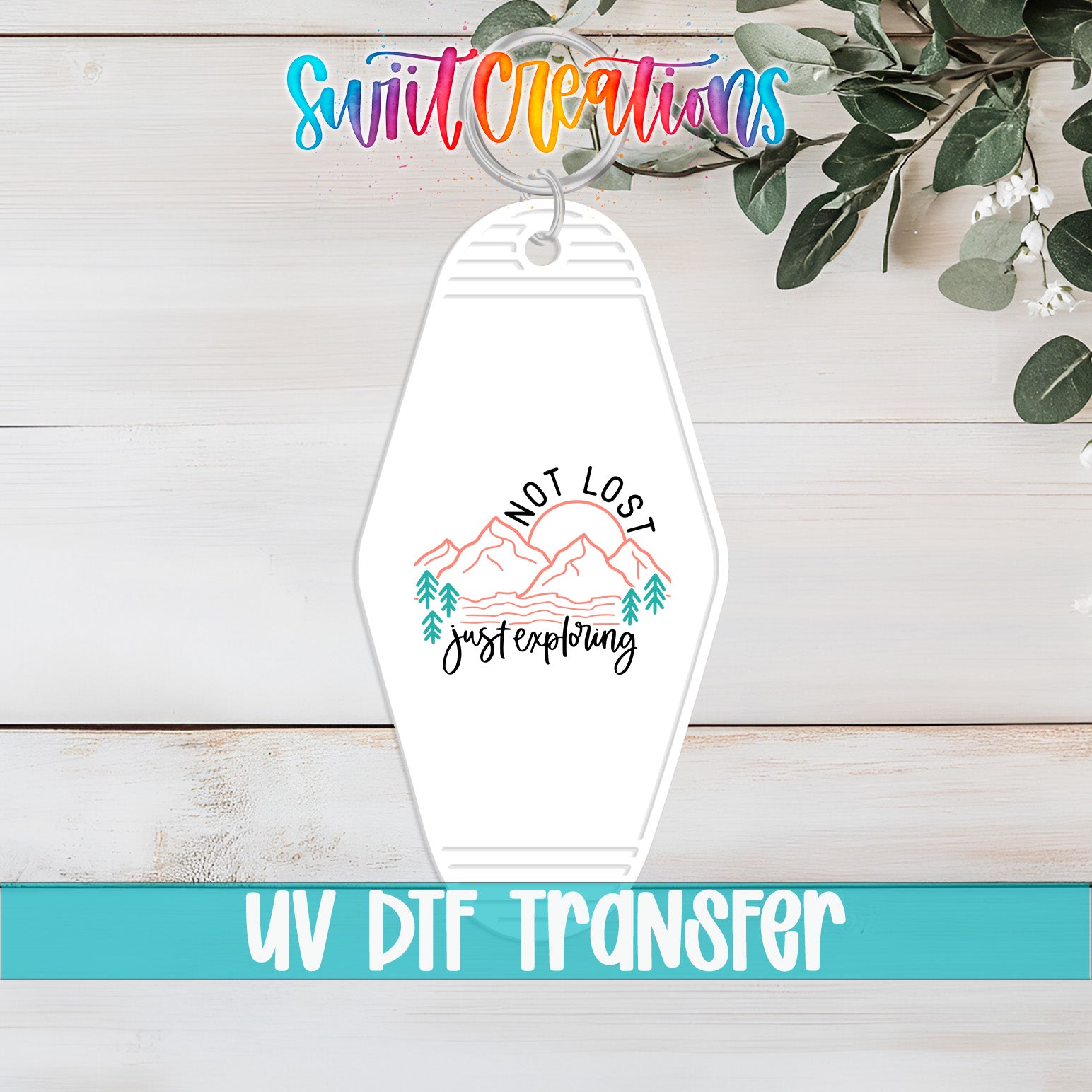 A keychain with a mountain landscape and the text "NOT LOST just exploring" printed on it, along with the text "UV DTF Transfer" below it.