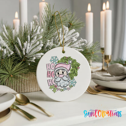 A white ceramic ornament with a Santa Claus design and the text "HOOK HOOK" is displayed on a table with candles and pine branches in the background.