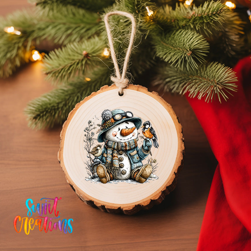 A wooden ornament featuring a snowman holding a bird is hanging on a Christmas tree, with a red cloth visible in the background.