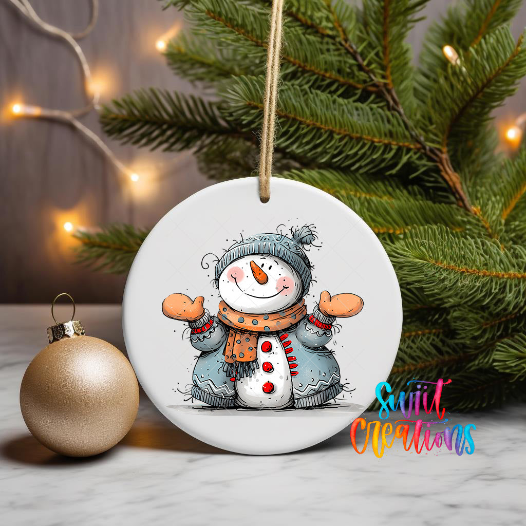 A white ceramic ornament featuring a snowman is displayed on a table, with a Christmas tree and a gold ornament in the background.