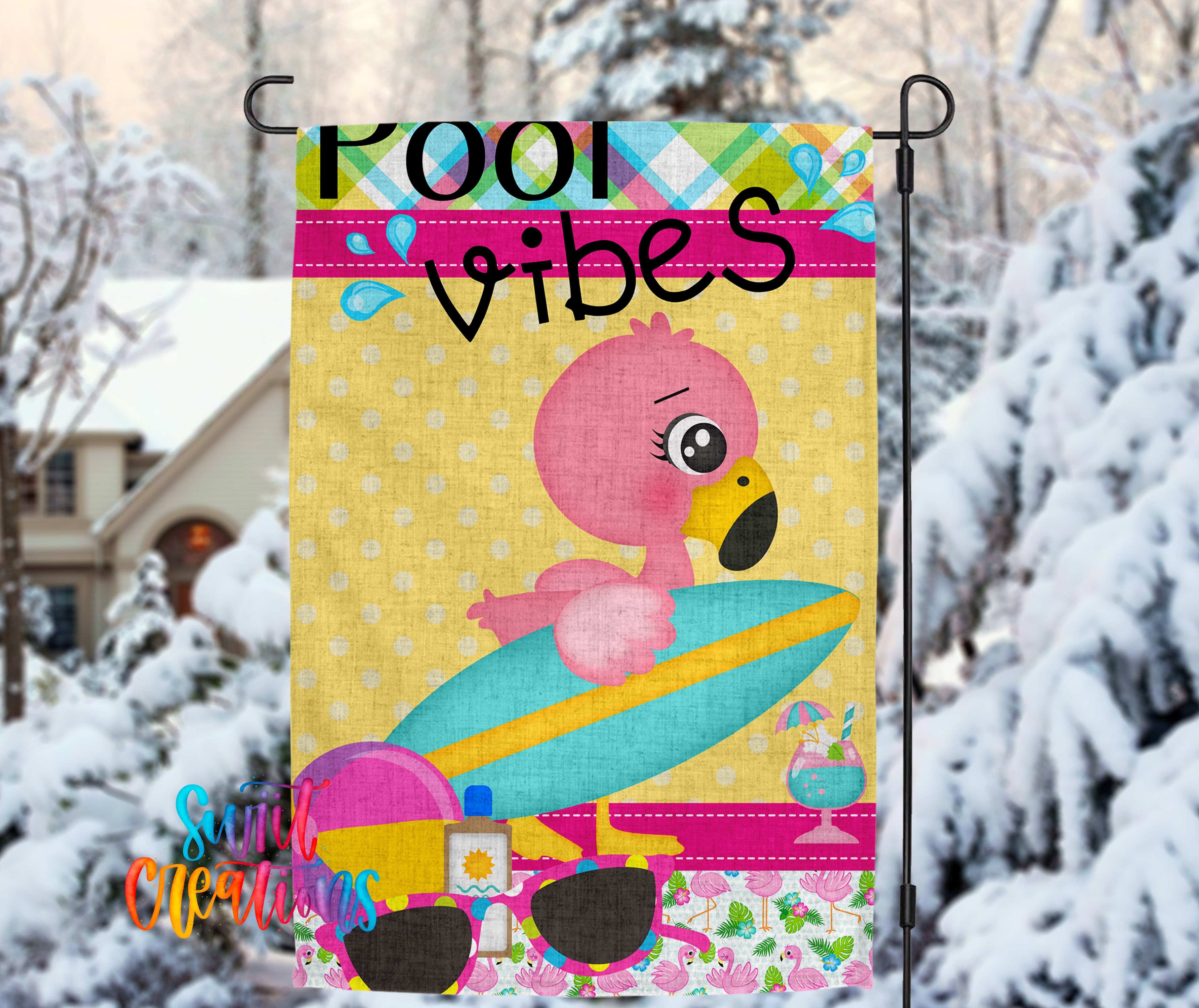 A colorful flag with a pink flamingo sitting on a surfboard, surrounded by snow-covered trees.