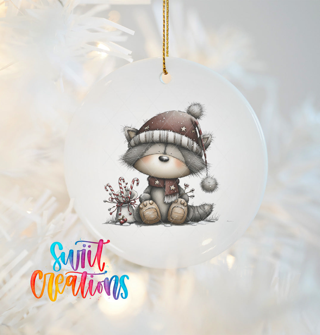 A ceramic ornament featuring a cute raccoon wearing a hat and scarf, sitting on a snowy surface with candy canes nearby.