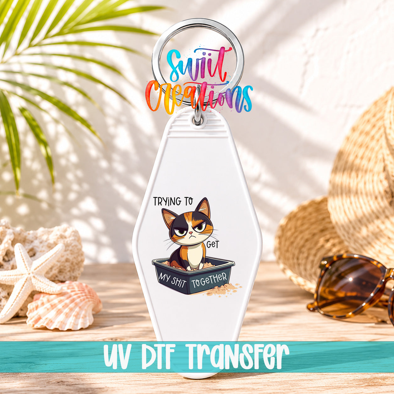 A keychain with a cartoon cat and the text "Trying to get my shit together" printed on it, along with a colorful ring and the text "UV DFT Transfer".