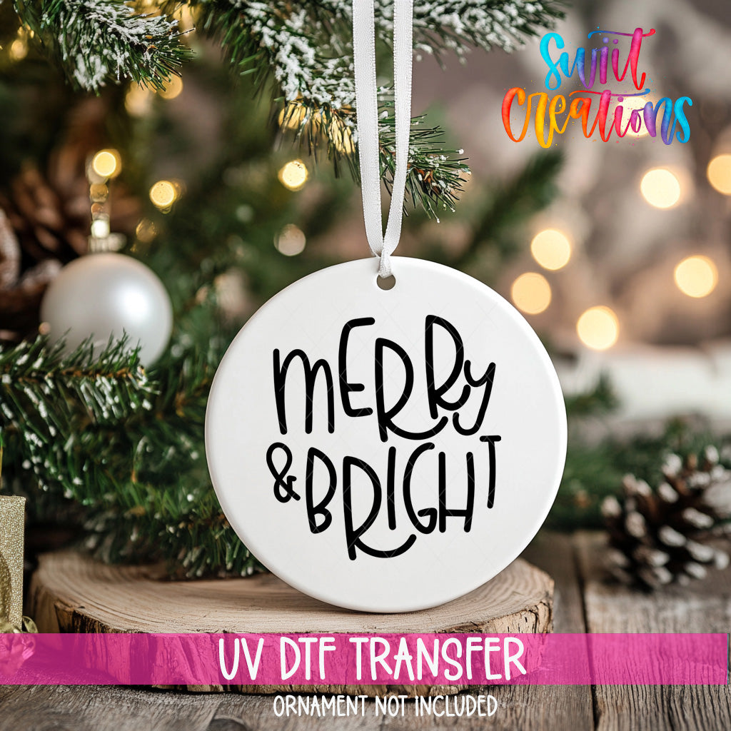 A white ornament with the text "MERRY & BRIGHT" hanging on a Christmas tree, with a blurred background of pine branches and twinkling lights.