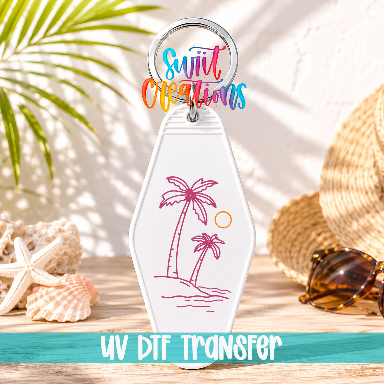 A keychain with a palm tree design and a sun illustration, placed on a wooden surface with sunglasses and a straw hat in the background.
