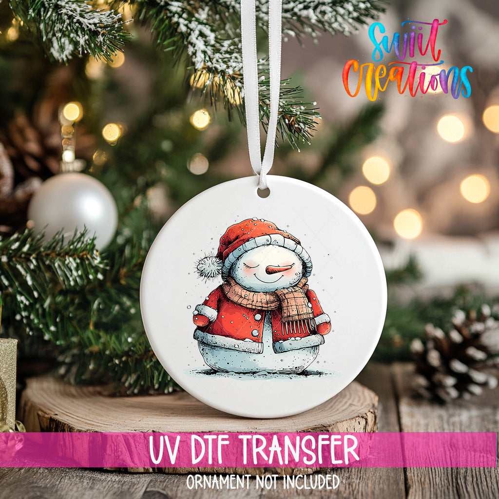 A white ceramic ornament featuring a snowman is hanging on a Christmas tree, with a blurred background of pine branches and twinkling lights.