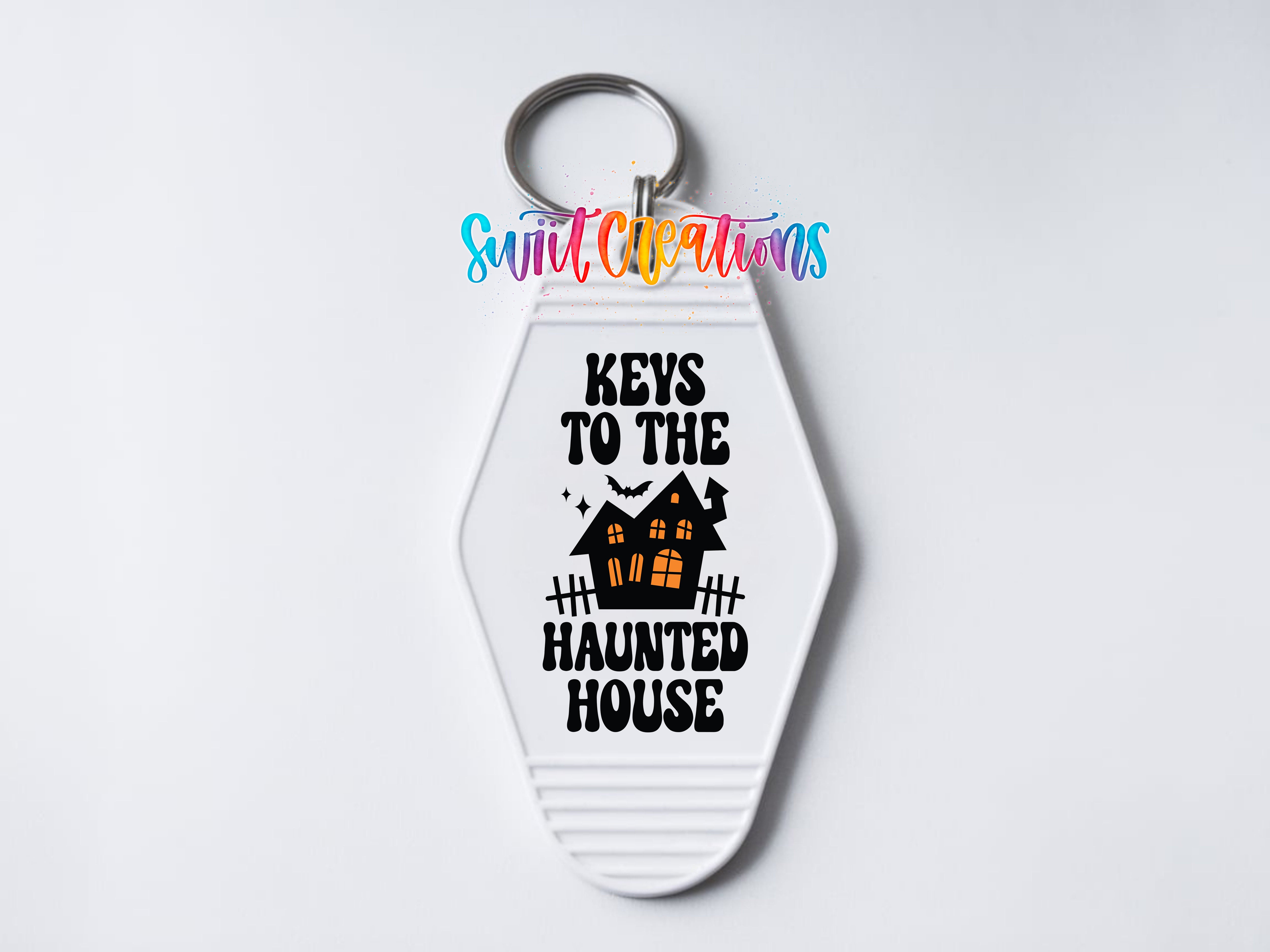 A keychain with the text "KEYS TO THE HAUNTED HOUSE" printed on it, along with a graphic of a house with bats and a spooky appearance.