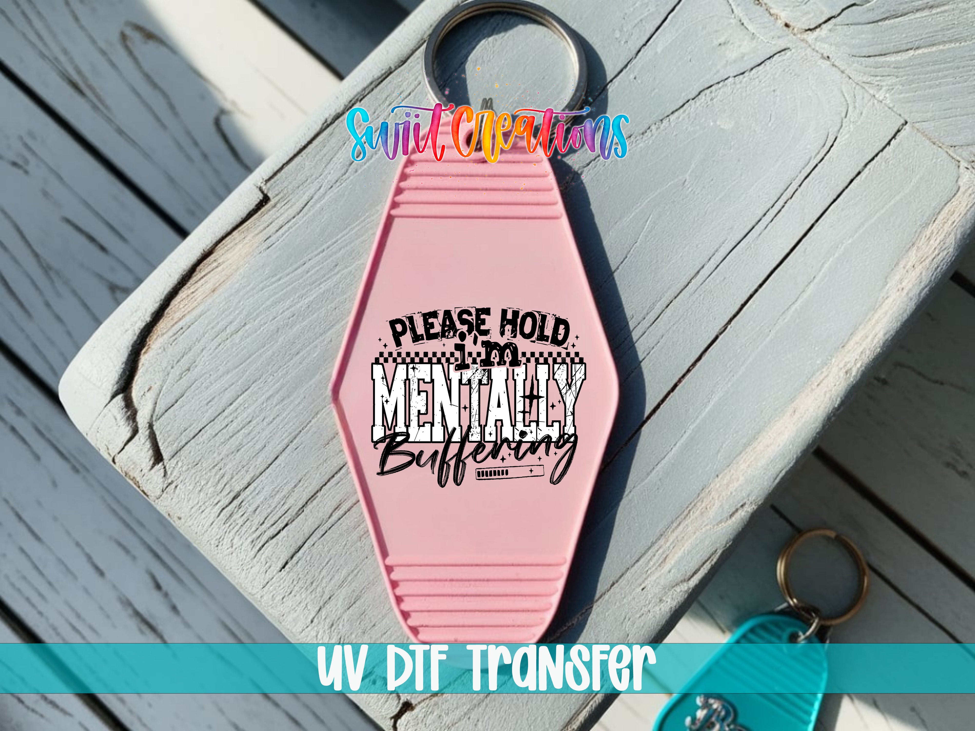 A pink keychain with a humorous text message printed on it, placed on a wooden surface.