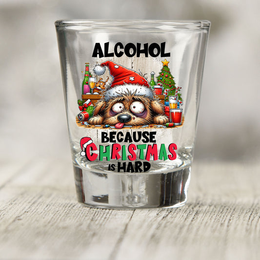 Alcohol Because Christmas is Hard shot glass UV DTF transfer with tired dog in a Santa hat with bottles and a tree on a clear shot glass