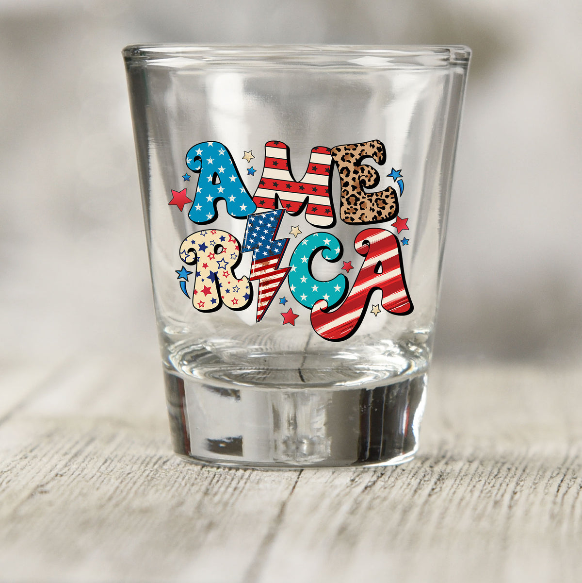America shot glass UV DTF transfer with star, stripe, and leopard print lettering on a clear shot glass