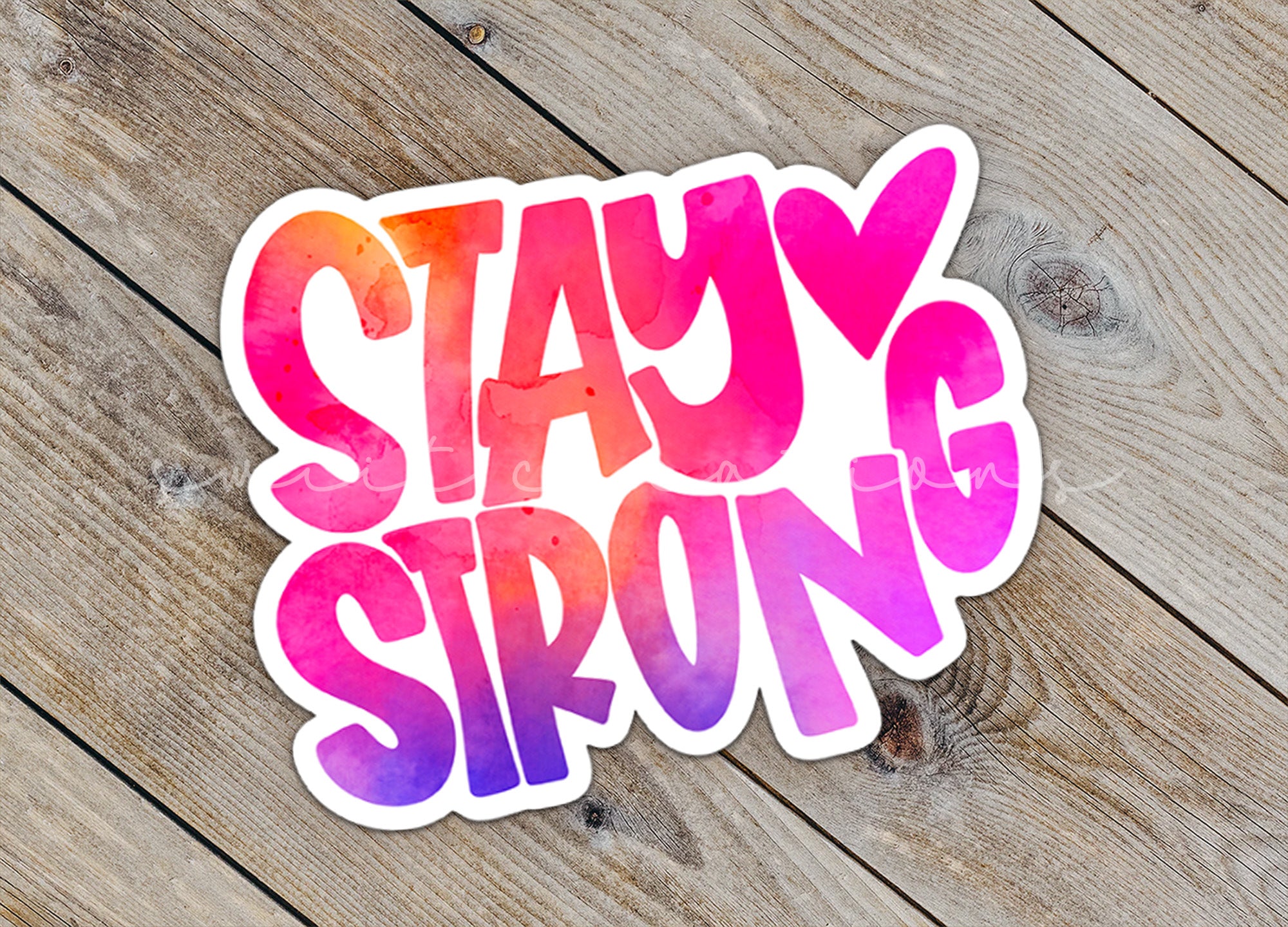 a sticker that says stay strong on a wooden surface