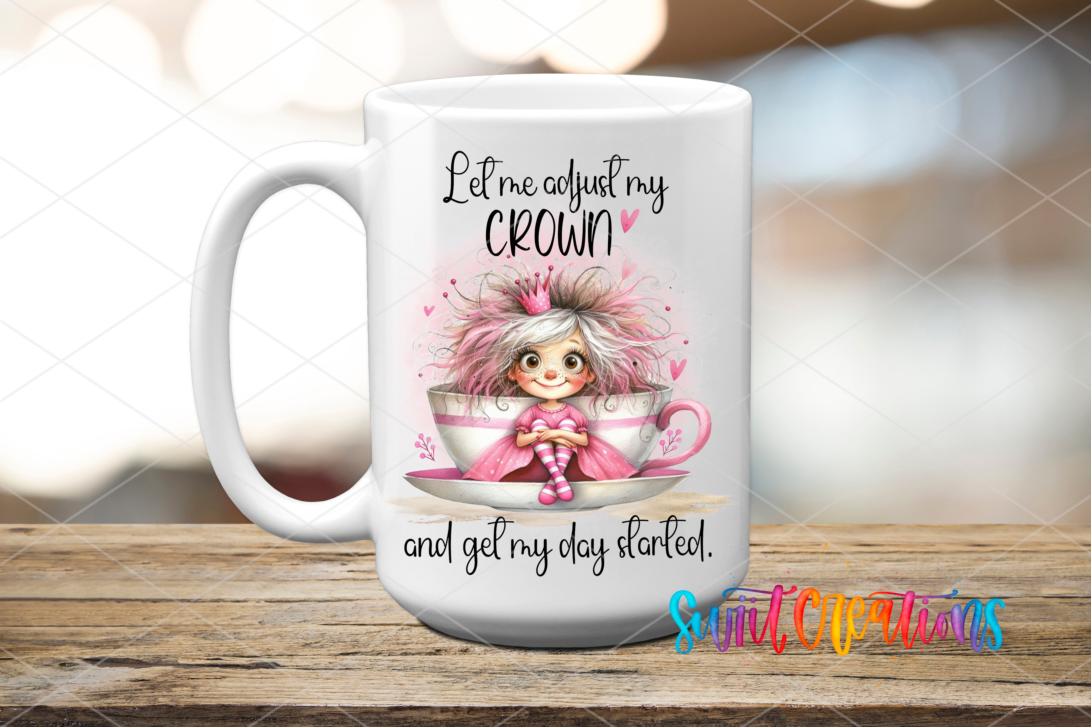 A white ceramic mug with a cartoon illustration of a young girl wearing a crown, sitting inside a teacup. The mug has text that reads "Let me just adjust my crown and get my day started."