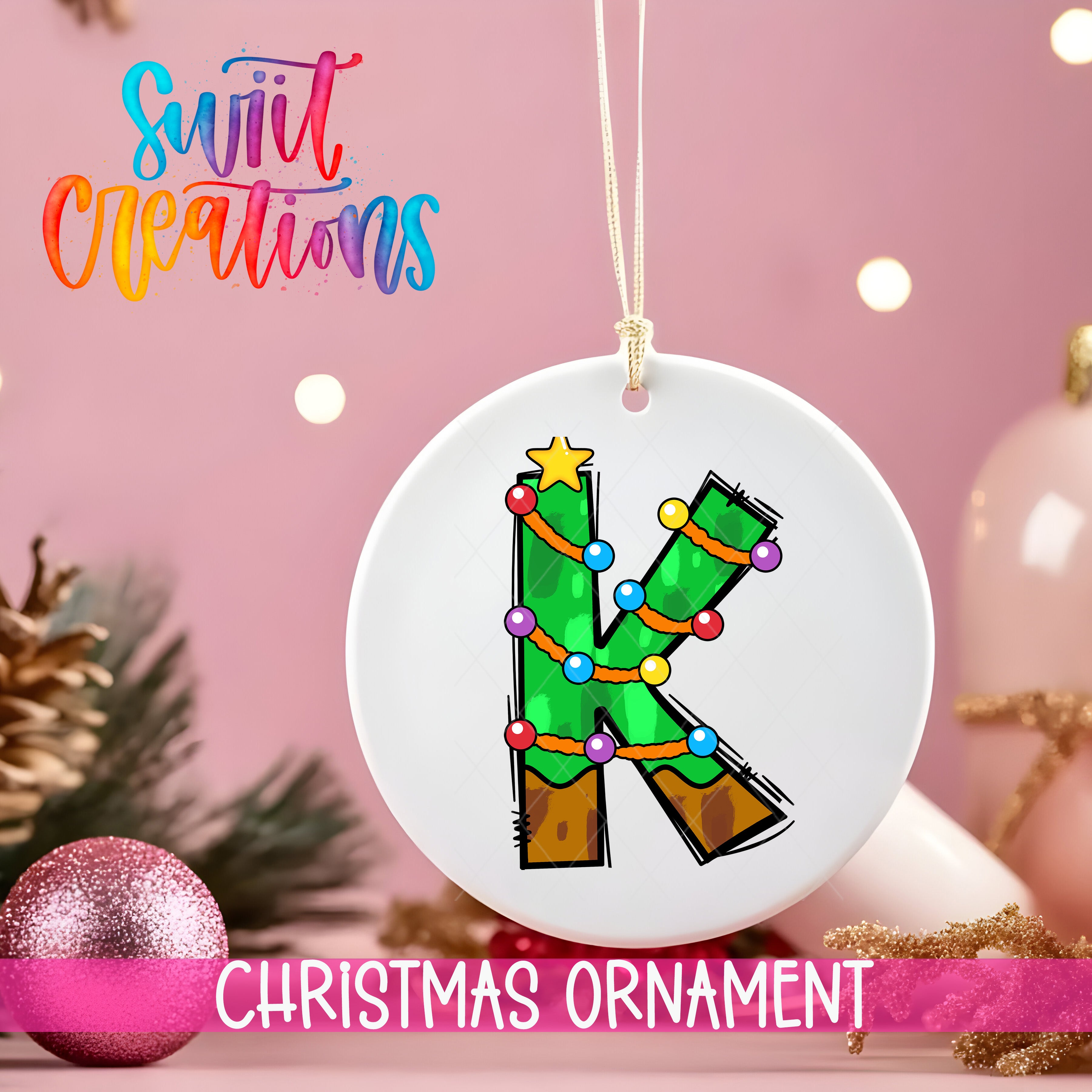A white Christmas ornament with a green tree design and colorful lights, hanging on a string.